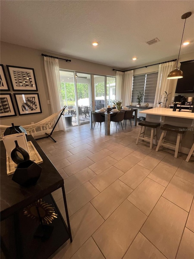 living room with recessed lighting, a textured ceiling, visible vents, and light tile patterned floors