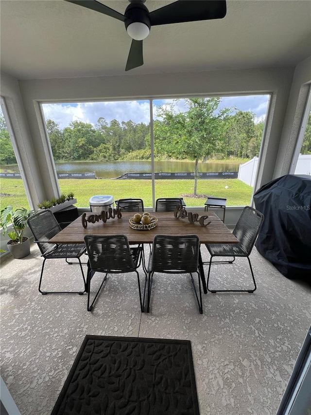 sunroom / solarium featuring a water view, ceiling fan, and outdoor dining space