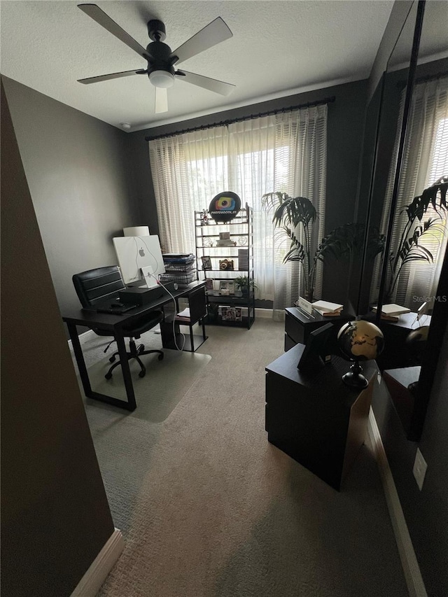 sitting room with carpet floors, baseboards, a ceiling fan, and a textured ceiling
