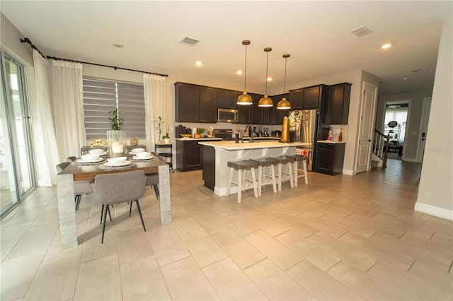 3920 Southern Vista Loop, Saint Cloud, FL 34772 - kitchen with appliances with stainless steel finishes, light countertops, a breakfast bar, a kitchen island with sink, and dark brown cabinetry