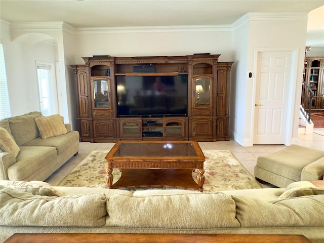 living area featuring light tile patterned floors, ornamental molding, and arched walkways