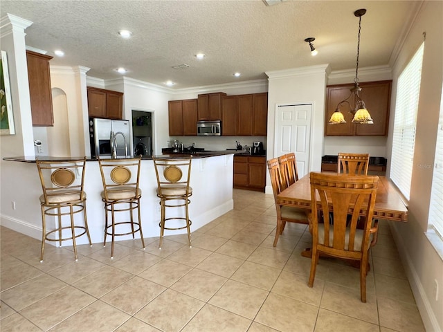kitchen with recessed lighting, a breakfast bar, a peninsula, dark countertops, and stainless steel appliances