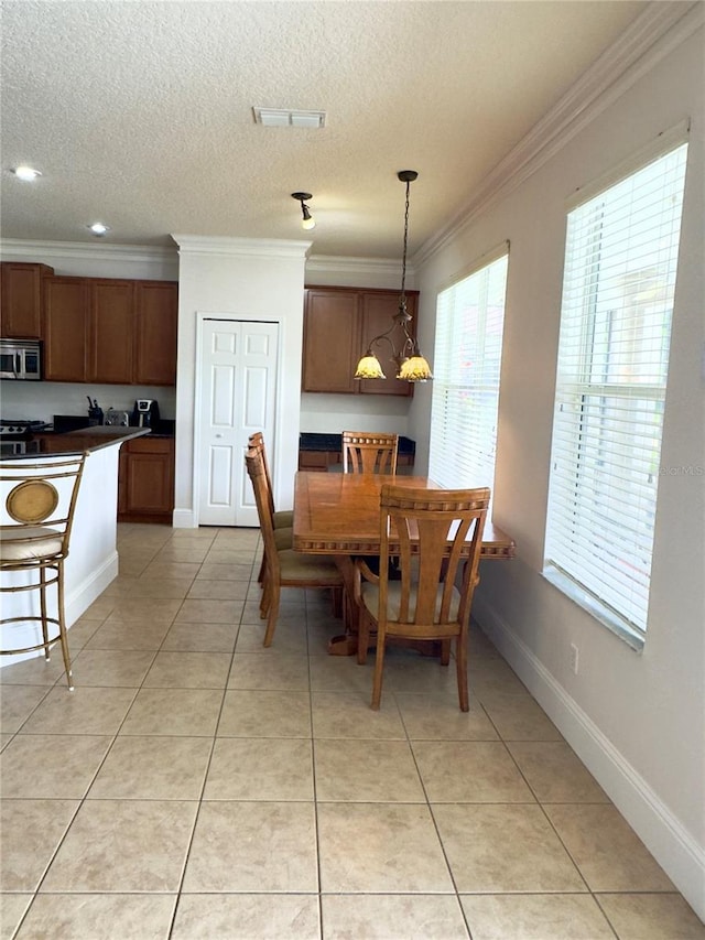 dining room featuring a textured ceiling, light tile patterned floors, baseboards, visible vents, and crown molding