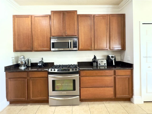 kitchen with stainless steel appliances, dark stone counters, and crown molding