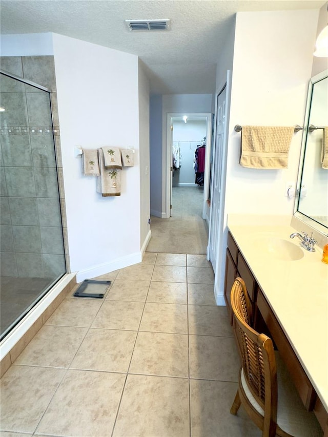 bathroom featuring a walk in closet, tile patterned floors, visible vents, and a shower stall