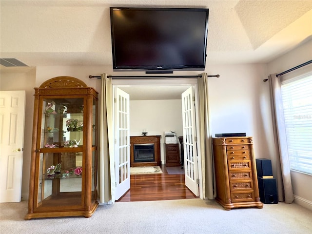 bedroom with french doors, carpet, visible vents, baseboards, and a glass covered fireplace