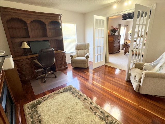office with french doors, a textured ceiling, and wood finished floors