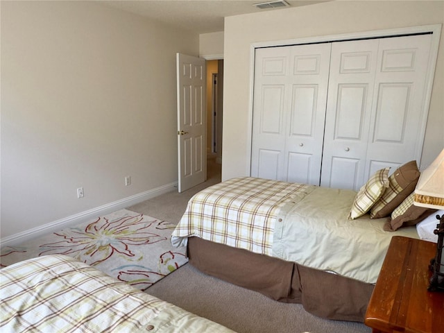 carpeted bedroom with a closet, visible vents, and baseboards