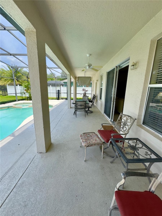 view of patio / terrace featuring a ceiling fan, outdoor dining space, fence, a fenced in pool, and glass enclosure