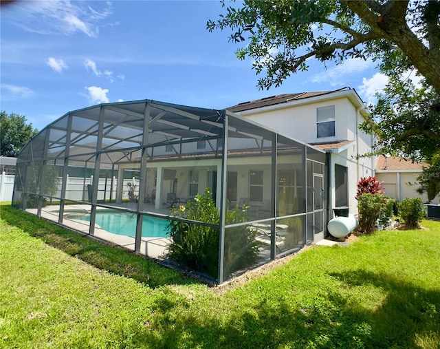 rear view of house with stucco siding, a lawn, an outdoor pool, and a patio area