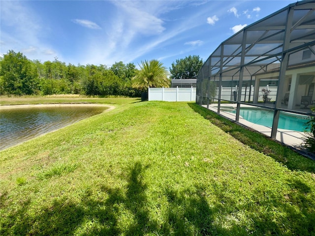view of yard with a water view, glass enclosure, an outdoor pool, and fence