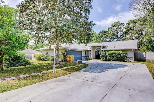 ranch-style home with a garage, stucco siding, fence, concrete driveway, and a front lawn