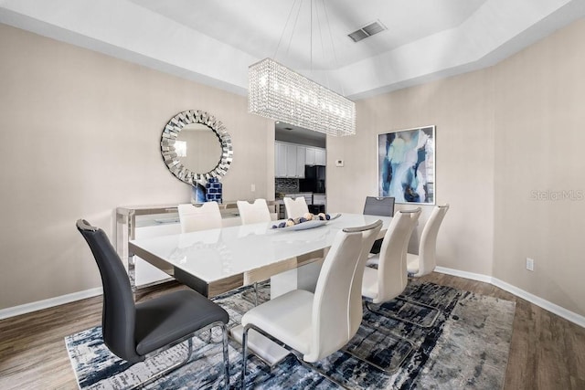 13044 Lakeshore Grove Dr, Winter Garden, FL 34787 - dining area with a chandelier, wood finished floors, baseboards, and a tray ceiling