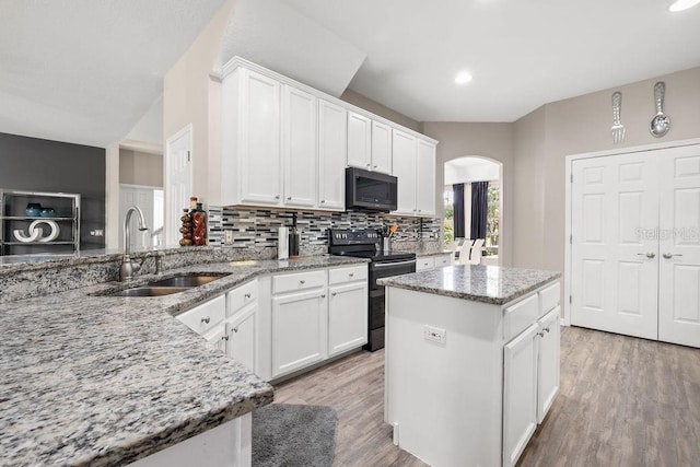 13044 Lakeshore Grove Dr, Winter Garden, FL 34787 - kitchen featuring black appliances, a sink, arched walkways, tasteful backsplash, and light stone countertops
