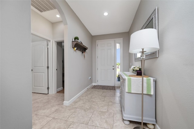 foyer featuring arched walkways, baseboards, light tile patterned floors, and visible vents