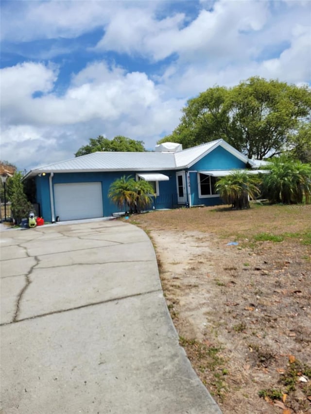 ranch-style home featuring driveway, metal roof, and a garage