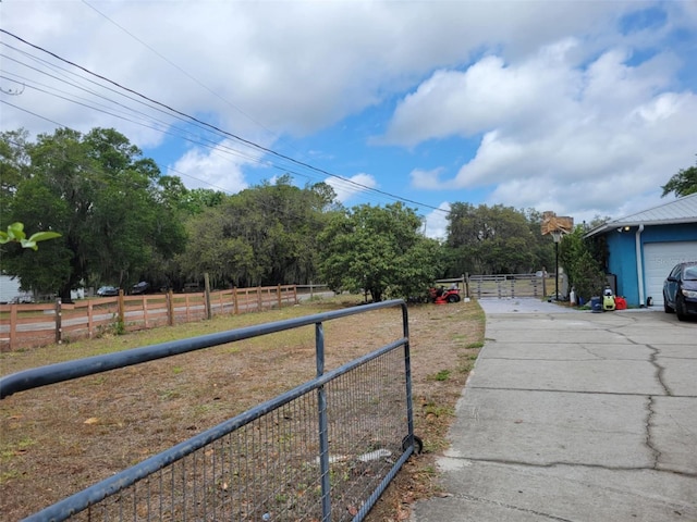 view of yard featuring concrete driveway, fence, and a garage