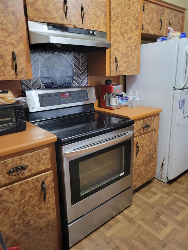 kitchen with light countertops, brown cabinetry, a toaster, under cabinet range hood, and stainless steel electric stove