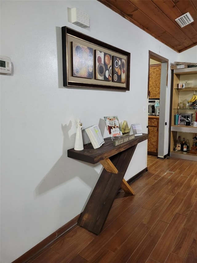 hallway featuring visible vents, baseboards, and wood finished floors