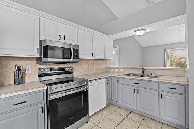 kitchen with light countertops, a textured ceiling, a sink, appliances with stainless steel finishes, and backsplash
