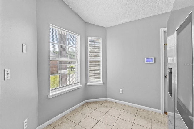 unfurnished room with baseboards, a textured ceiling, and light tile patterned flooring
