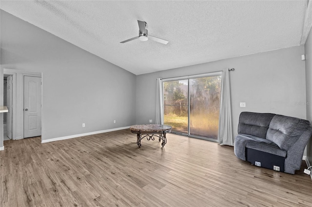unfurnished room with ceiling fan, a textured ceiling, vaulted ceiling, wood finished floors, and baseboards