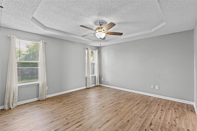 unfurnished room with baseboards, a ceiling fan, a textured ceiling, and wood finished floors