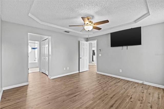 unfurnished bedroom with visible vents, wood finished floors, baseboards, a textured ceiling, and a ceiling fan