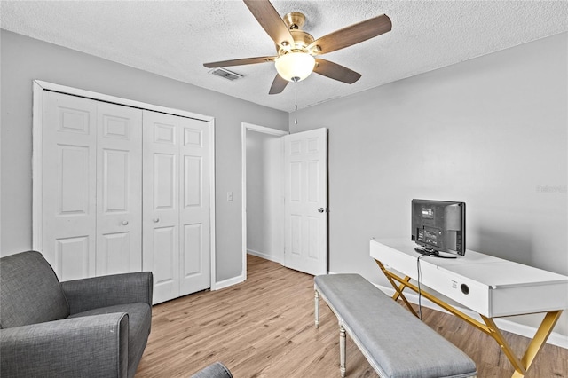 home office with a ceiling fan, a textured ceiling, visible vents, light wood-type flooring, and baseboards