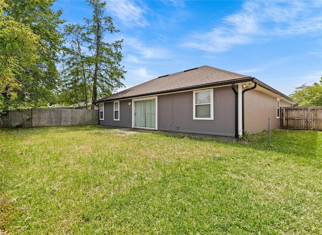 back of house with a fenced backyard and a yard