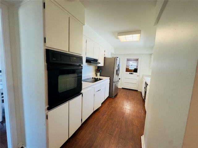 1419 Ave D NE, Winter Haven, FL 33881 - kitchen with black appliances, under cabinet range hood, dark wood-type flooring, light countertops, and white cabinetry