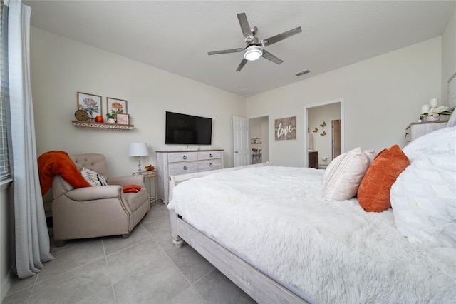 bedroom with connected bathroom, light tile patterned floors, visible vents, and ceiling fan