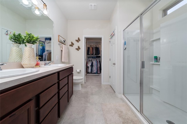 bathroom featuring a stall shower, tile patterned floors, double vanity, and a sink
