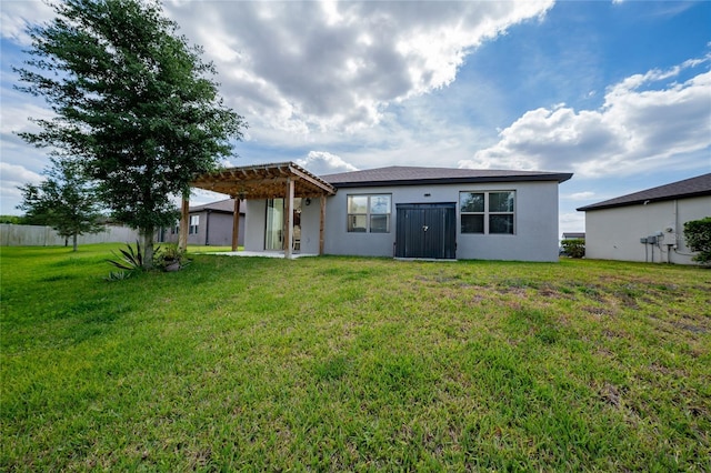 back of property with stucco siding, a pergola, a lawn, and fence
