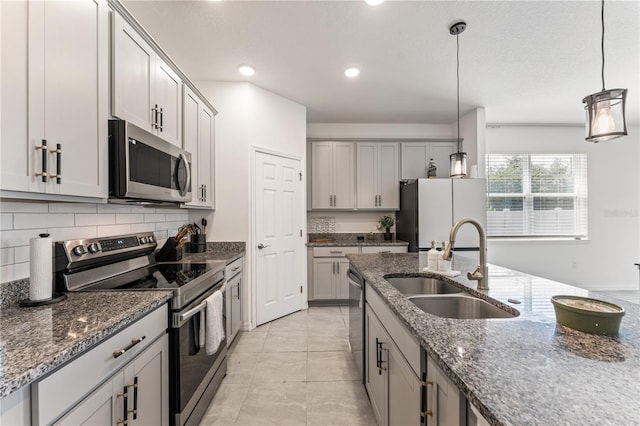 kitchen with dark stone countertops, backsplash, appliances with stainless steel finishes, and a sink