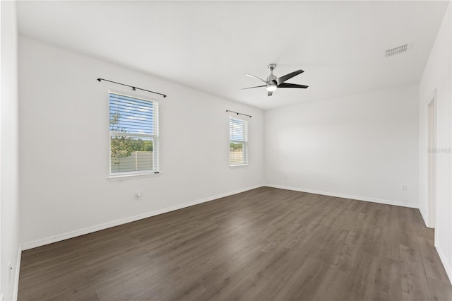 empty room with baseboards, dark wood-style flooring, ceiling fan, and visible vents