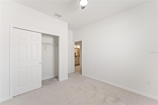 unfurnished bedroom featuring baseboards, light carpet, a closet, and visible vents