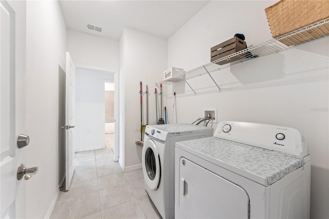 laundry area featuring light tile patterned floors, baseboards, washer and dryer, visible vents, and laundry area