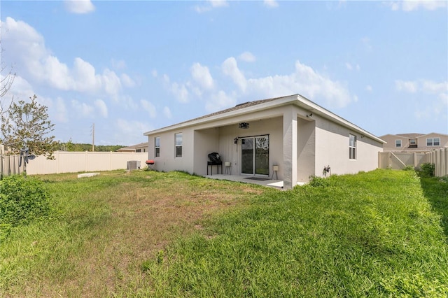 back of property featuring a lawn, a patio, central air condition unit, stucco siding, and a fenced backyard