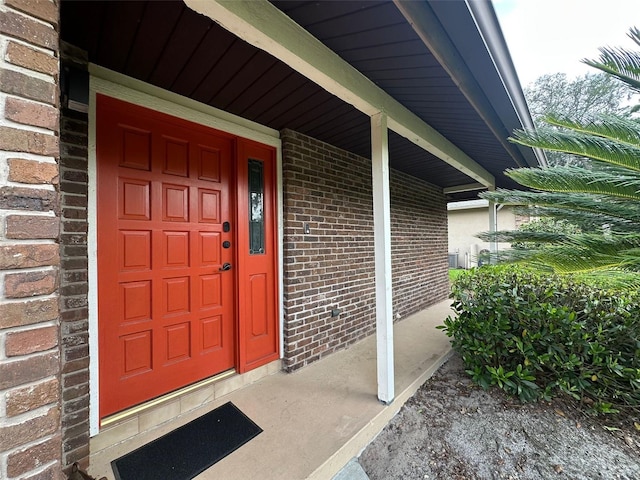 doorway to property with covered porch and brick siding