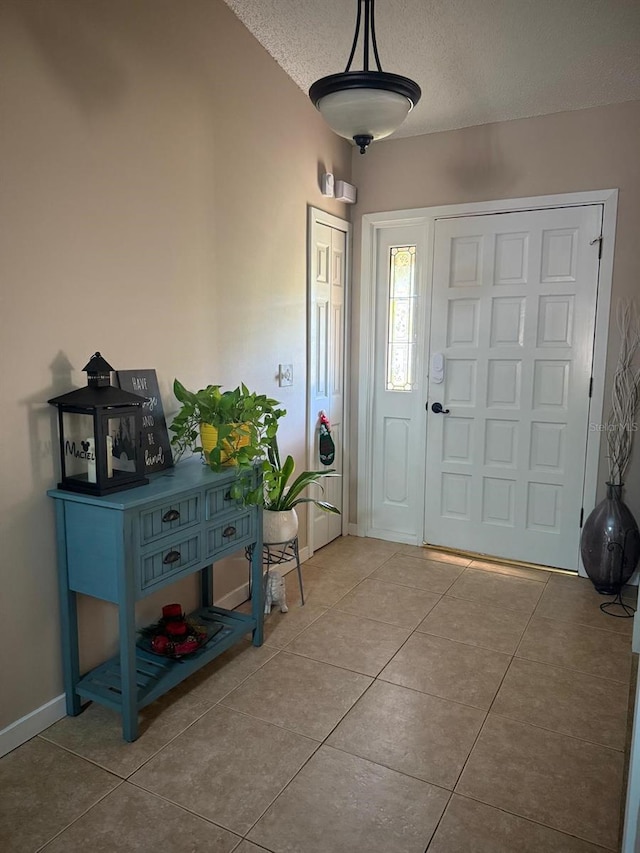 tiled foyer entrance with baseboards and a textured ceiling