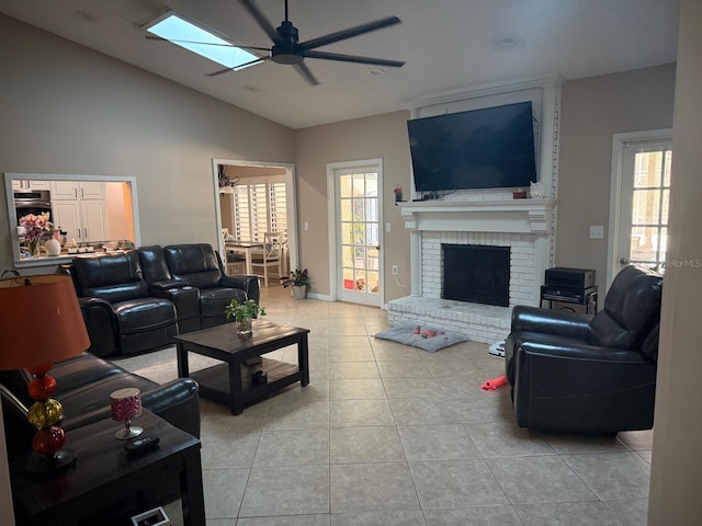 living room featuring a ceiling fan, lofted ceiling, a fireplace, and light tile patterned floors