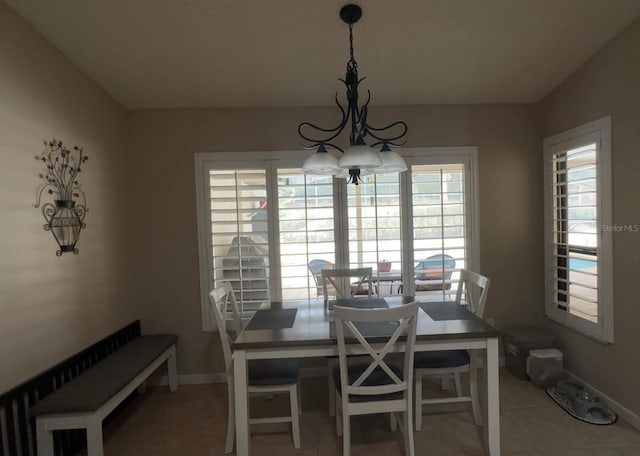 tiled dining space featuring baseboards and a notable chandelier