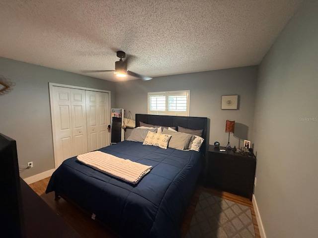 bedroom with a closet, wood finished floors, a textured ceiling, ceiling fan, and baseboards