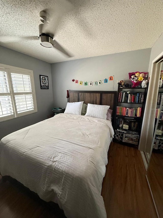 bedroom with a textured ceiling, a ceiling fan, and wood finished floors