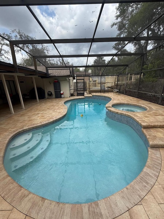 view of pool with a patio area, a pool with connected hot tub, and a lanai