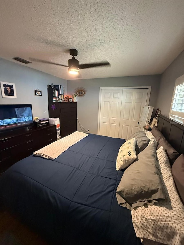 bedroom featuring a textured ceiling, a closet, a ceiling fan, and visible vents