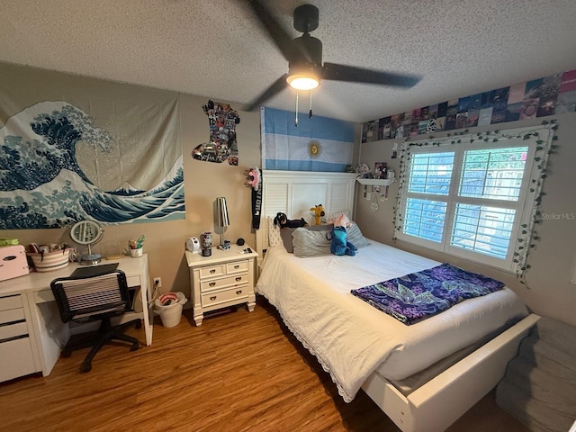 bedroom featuring ceiling fan, a textured ceiling, and wood finished floors