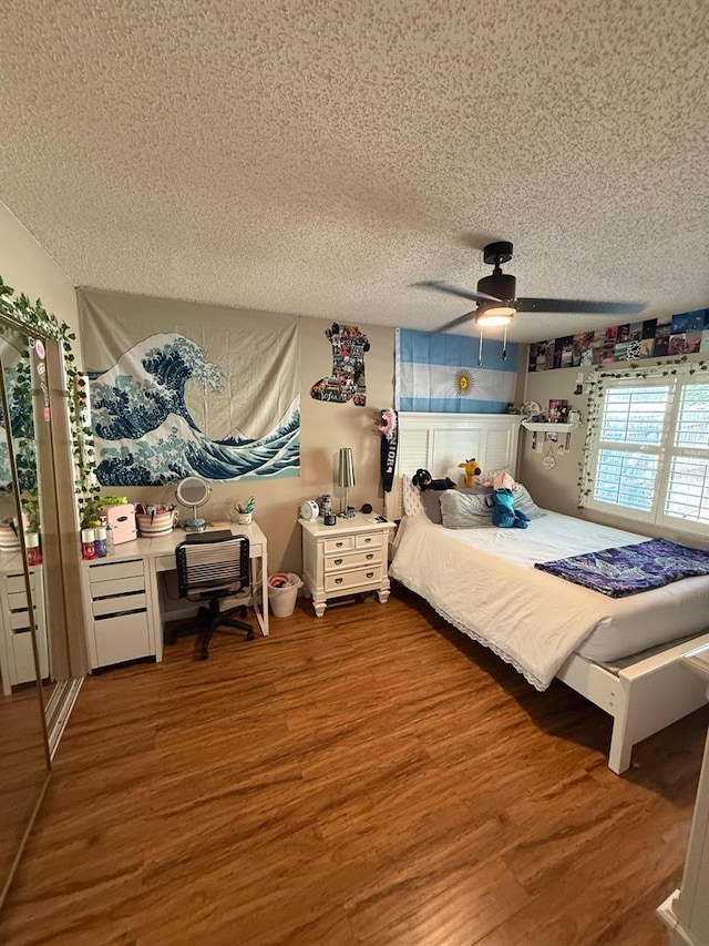 bedroom featuring a textured ceiling, wood finished floors, and ceiling fan