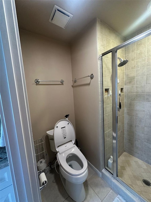 bathroom featuring tile patterned flooring, toilet, a shower stall, and visible vents